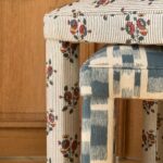Deux tabourets Mary, l’un en tissu fleuri, l’autre en ikat bleu, devant une boiserie