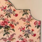 Détail de la tête de lit Georgie en tissu fleuri, passepoil vert